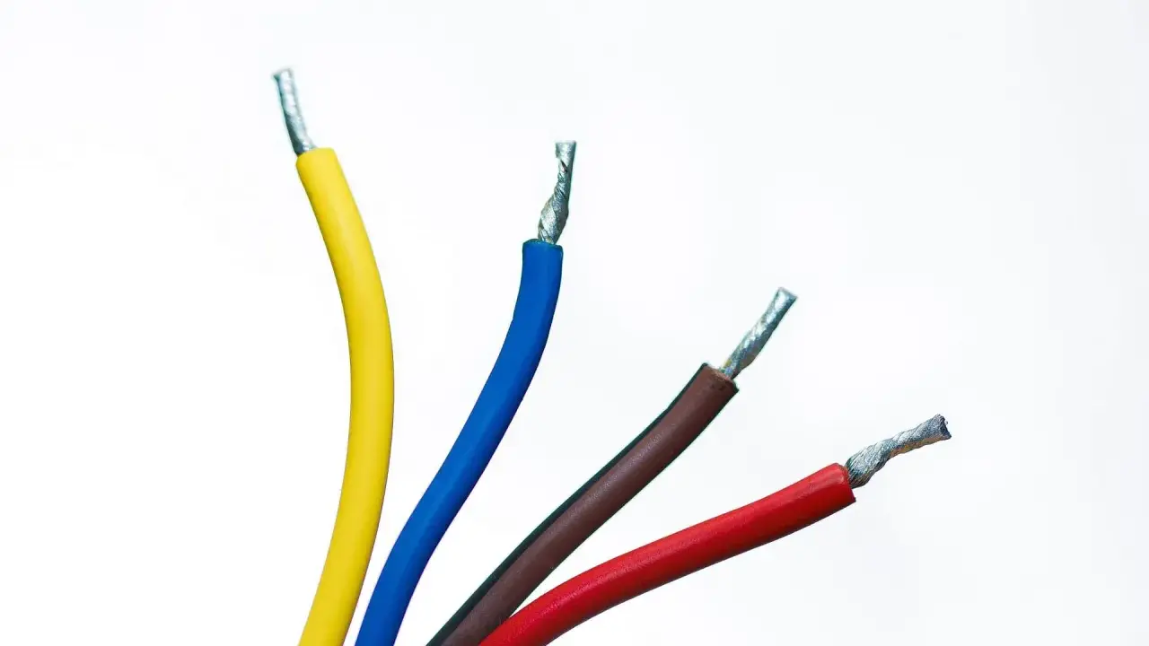 Quatre fils électriques dénudés : jaune, fil bleu électrique, marron et rouge, sur fond blanc.