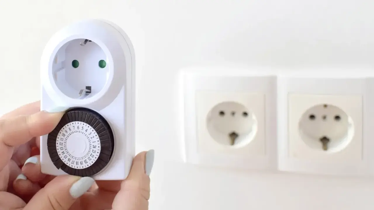 Une main ajuste le cadran d'un minuteur mécanique, montrant comment fonctionne un minuteur pour programmer des appareils électriques.
