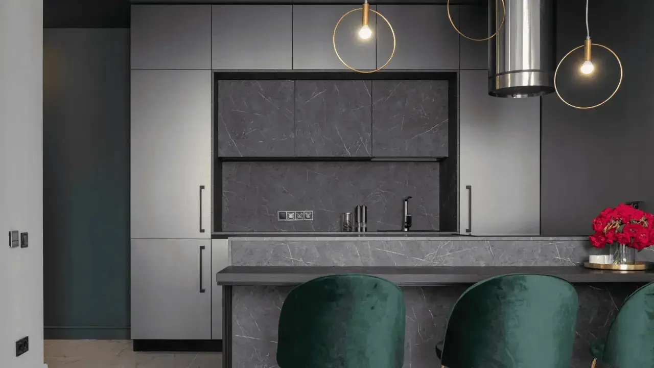 Cuisine moderne avec armoires grises, îlot en marbre et suspensions dorées. Pour un éclairage optimal, combien de lumen pour une cuisine ?