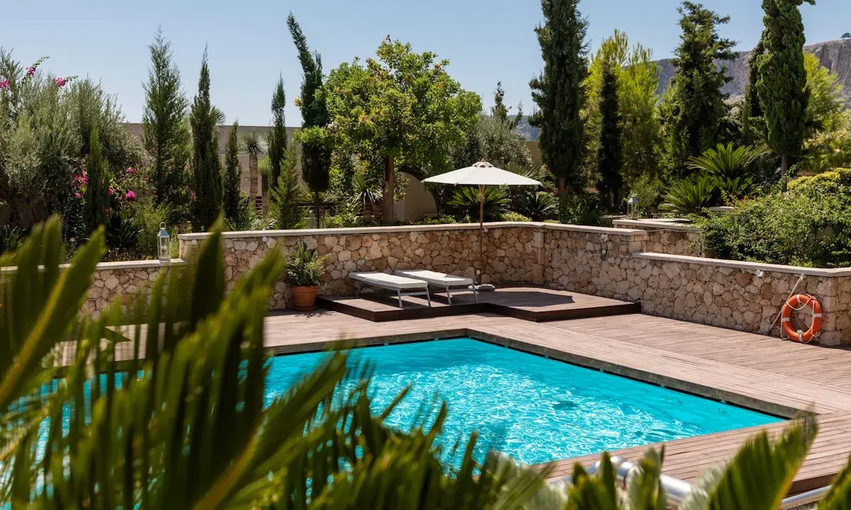 Piscine luxueuse avec terrasse en bois, transats, parasol et bouée. La protection électrique de la piscine est assurée pour une baignade en toute sécurité.