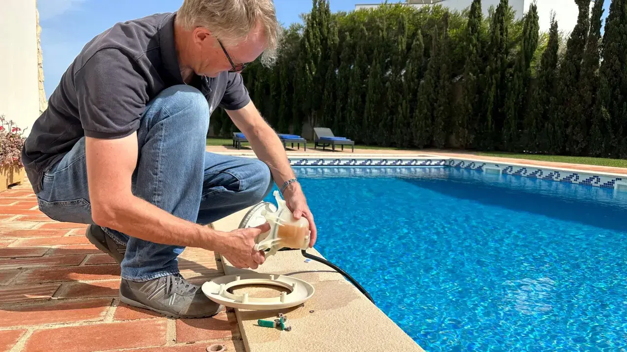 Homme près d'une piscine, tenant une pièce de la pompe. Il vérifie le disjoncteur pompe piscine pour s'assurer que tout fonctionne.