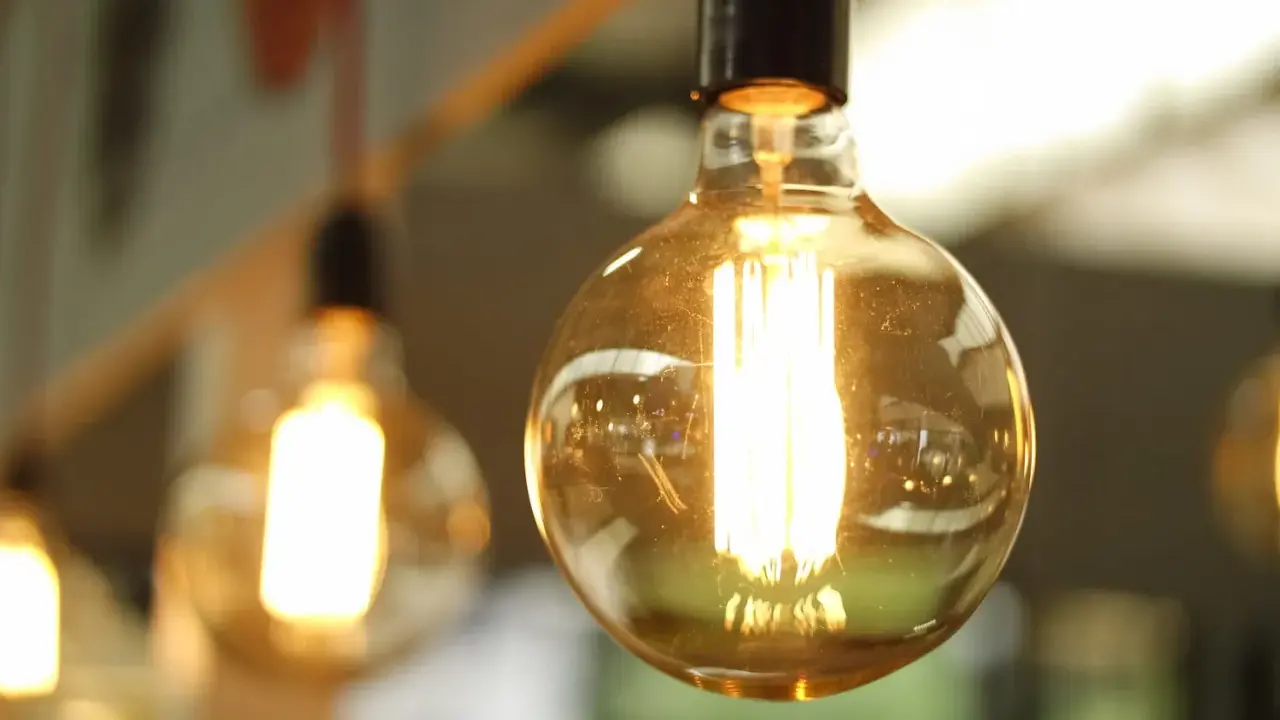 Plusieurs ampoules LED de différents types, avec un filament visible, diffusent une lumière chaude et dorée.