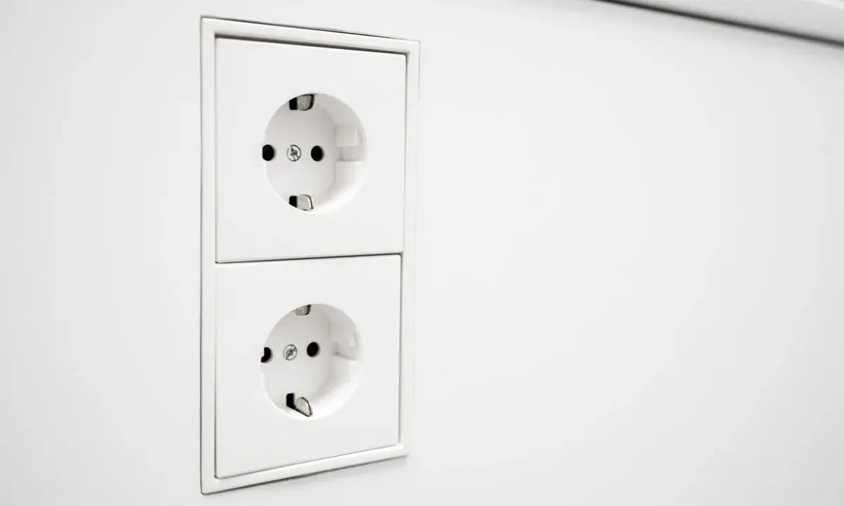 Deux prises EU blanches, alignées verticalement sur un mur blanc. Prêtes à alimenter vos appareils.