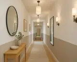 Éclairage couloir long et étroit avec appliques murales et suspensions cylindriques. Miroirs et tableaux décorent les murs.