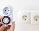 Une main ajuste le cadran d'un minuteur mécanique, montrant comment fonctionne un minuteur pour programmer des appareils électriques.