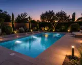Belle piscine illuminée au crépuscule. Le disjoncteur de l'éclairage piscine est visible sur la gauche, discret mais essentiel.