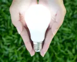 Mains de femme tenant une ampoule flamme torsadée lumineuse, symbole d'une idée brillante et d'énergie verte.