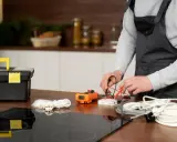 Un technicien vérifie un fusible pour plaque induction avec un multimètre. Outils et câbles à proximité.