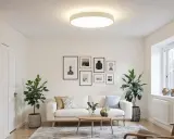 Salon moderne avec un canapé blanc, des plantes vertes et un éclairage doux d'une **led plate** au plafond.