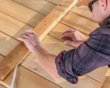 Un homme installe un ruban LED sur une structure en bois. Il réfléchit à quel ruban LED choisir pour son projet d'éclairage extérieur.