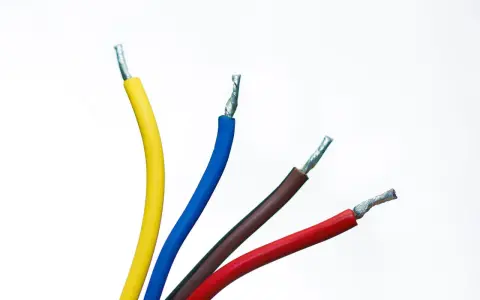 Quatre fils électriques dénudés : jaune, fil bleu électrique, marron et rouge, sur fond blanc.