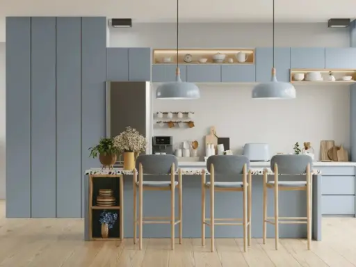 Cuisine moderne aux meubles bleus doux, avec un îlot central et des tabourets. L'éclairage doux crée une ambiance couleur blanc chaud.