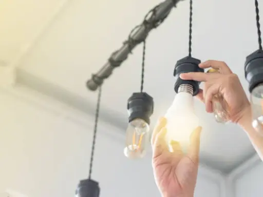 Main d'une personne installant une ampoule gradable dans un lustre.