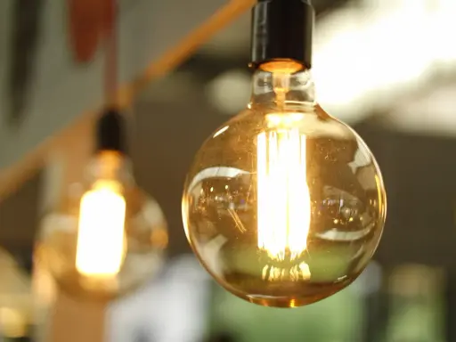 Plusieurs ampoules LED de différents types, avec un filament visible, diffusent une lumière chaude et dorée.