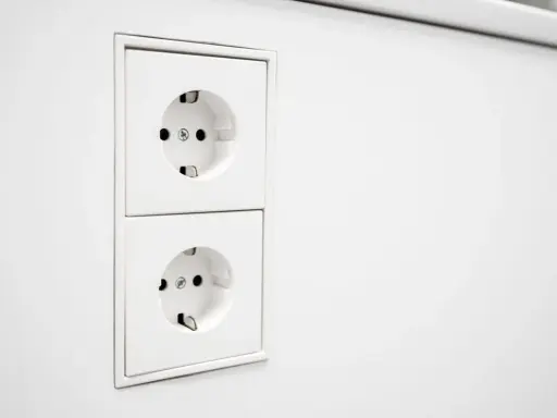 Deux prises EU blanches, alignées verticalement sur un mur blanc. Prêtes à alimenter vos appareils.