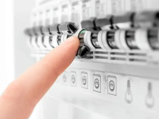 Doigt actionnant un disjoncteur dans un tableau électrique. Aide à comprendre quel disjoncteur différentiel choisir pour votre installation.