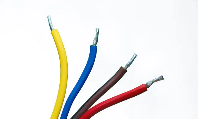 Quatre fils électriques dénudés : jaune, fil bleu électrique, marron et rouge, sur fond blanc.