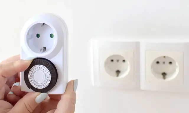 Une main ajuste le cadran d'un minuteur mécanique, montrant comment fonctionne un minuteur pour programmer des appareils électriques.