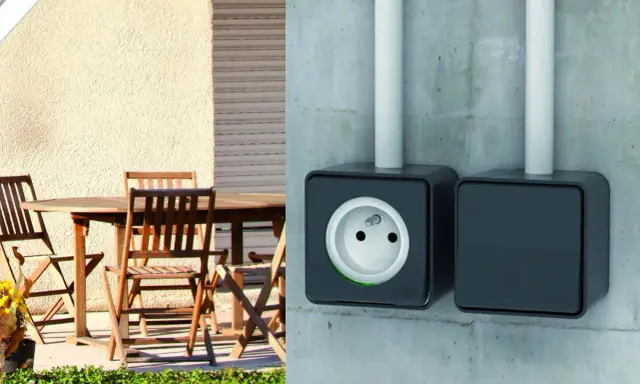 Branchement prise extérieur sur mur de béton. Une prise électrique noire est visible, avec une autre à côté. Une table et des chaises en bois sont sur une terrasse.