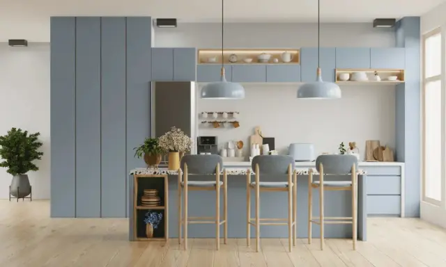 Cuisine moderne aux meubles bleus doux, avec un îlot central et des tabourets. L'éclairage doux crée une ambiance couleur blanc chaud.