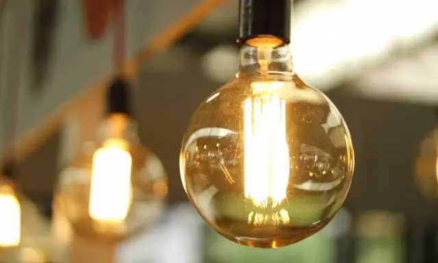 Plusieurs ampoules LED de différents types, avec un filament visible, diffusent une lumière chaude et dorée.