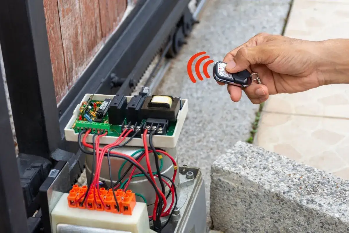 Main d'une personne tenant une télécommande pour activer le disjoncteur du portail électrique.
