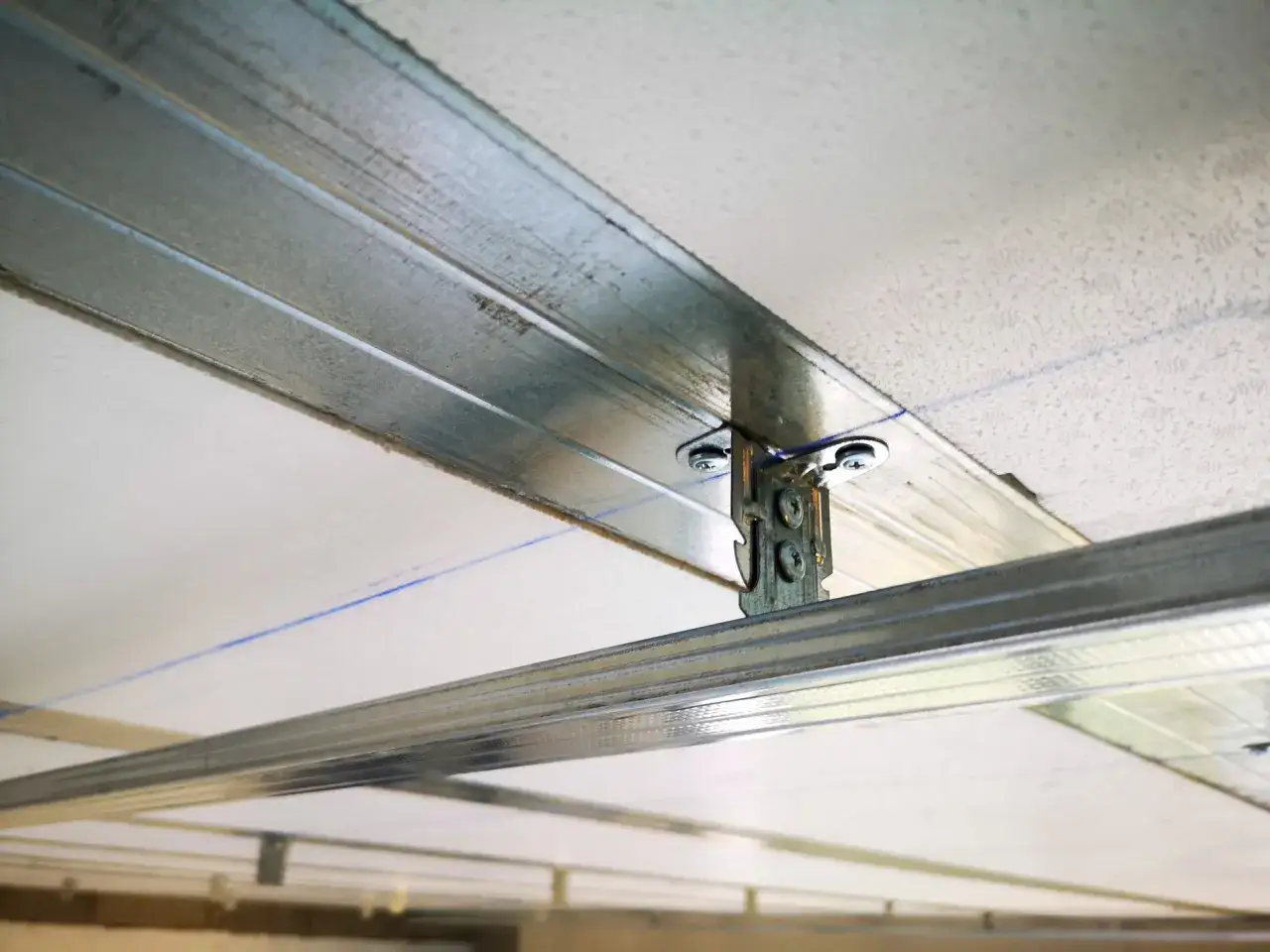 Structure m&eacute;tallique pour un faux plafond, avec un &eacute;l&eacute;ment de fixation visible. Ce kit fixation plafonnier assure la solidit&eacute; de l'ensemble.