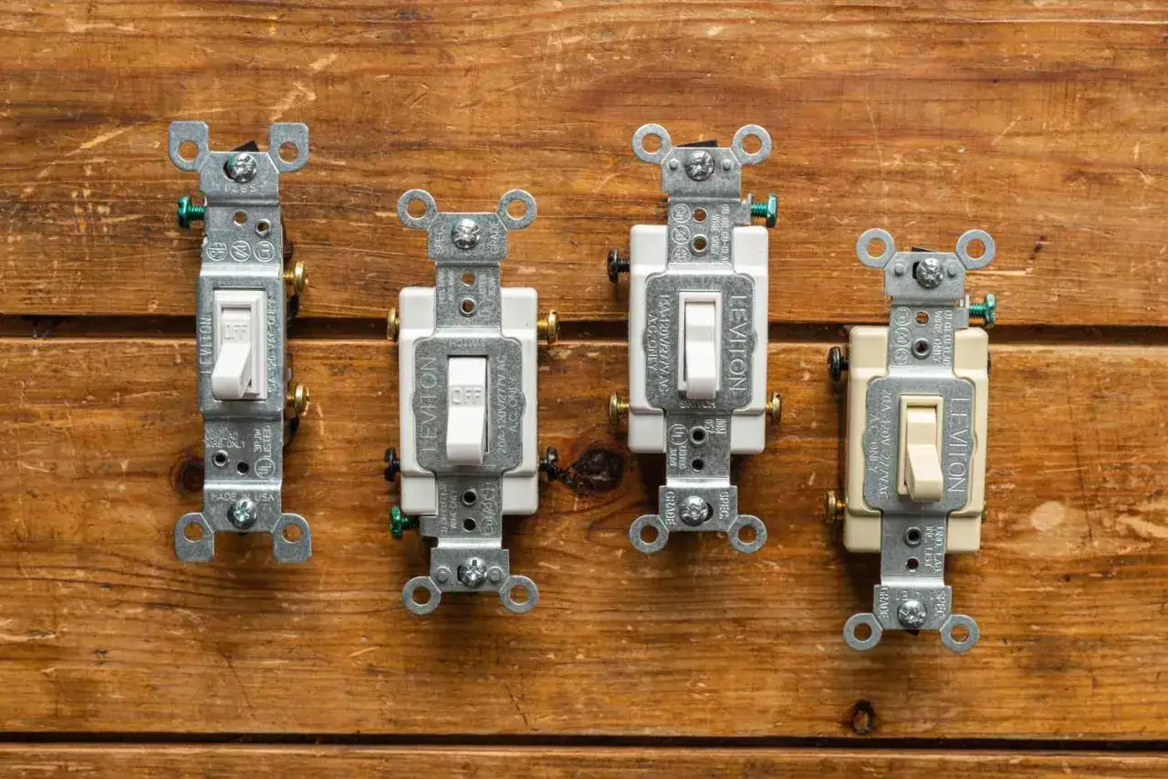 Quatre interrupteurs Leviton, dont un interrupteur va et vient ou poussoir, sur fond de bois.